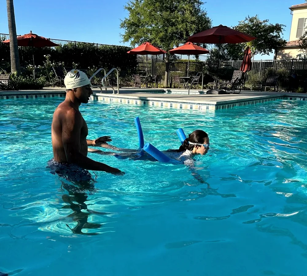 A student swimming during a private lesson with their coach